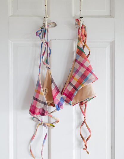 Colorful plaid bikini set hanging on a rack against a white door.